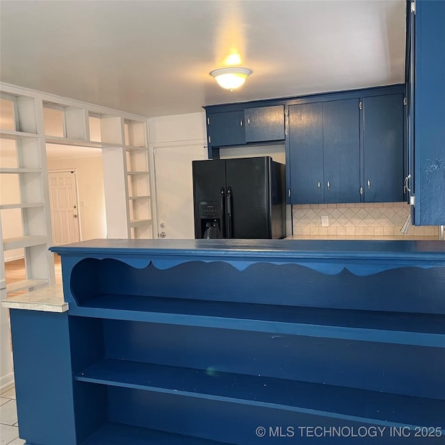 kitchen featuring open shelves, black fridge, decorative backsplash, light tile patterned flooring, and blue cabinets