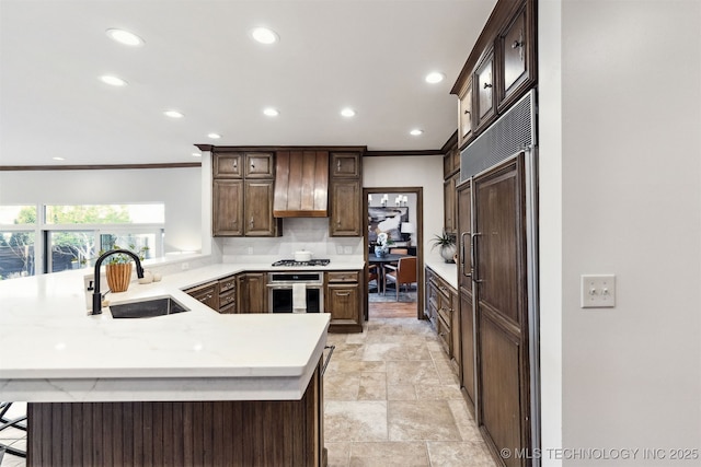 kitchen featuring a sink, a peninsula, stainless steel appliances, recessed lighting, and crown molding