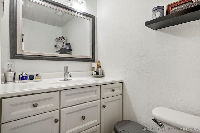 half bathroom with toilet, vanity, and a textured wall
