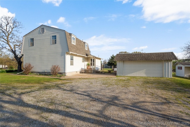 14531 S 107th W Ave, Sapulpa, OK 74066 - back of house with an outdoor structure, a detached garage, a patio area, a gambrel roof, and a shingled roof