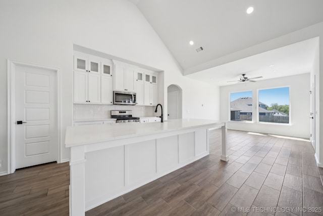 2916 S 8th St, Broken Arrow, OK 74012 - kitchen with stainless steel appliances, arched walkways, a large island with sink, dark wood-type flooring, and high vaulted ceiling
