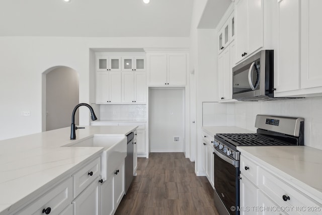2916 S 8th St, Broken Arrow, OK 74012 - kitchen featuring stainless steel appliances, arched walkways, white cabinetry, backsplash, and glass insert cabinets