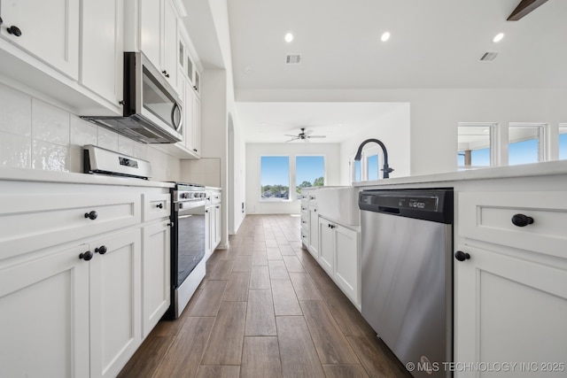 2916 S 8th St, Broken Arrow, OK 74012 - kitchen with appliances with stainless steel finishes, dark wood-style floors, white cabinets, backsplash, and ceiling fan