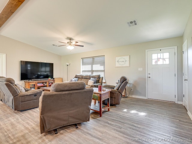 living room featuring light wood-type flooring, a ceiling fan, vaulted ceiling, visible vents, and baseboards