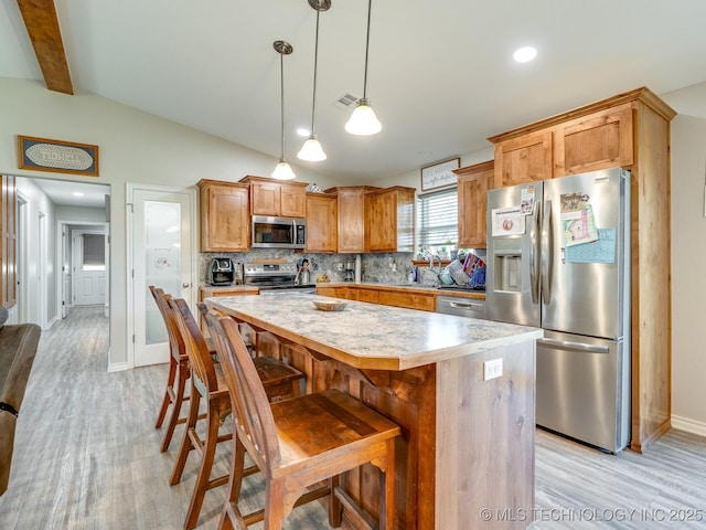 kitchen featuring decorative backsplash, light wood finished floors, lofted ceiling with beams, and stainless steel appliances