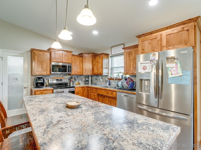 kitchen with tasteful backsplash, vaulted ceiling, appliances with stainless steel finishes, pendant lighting, and a sink