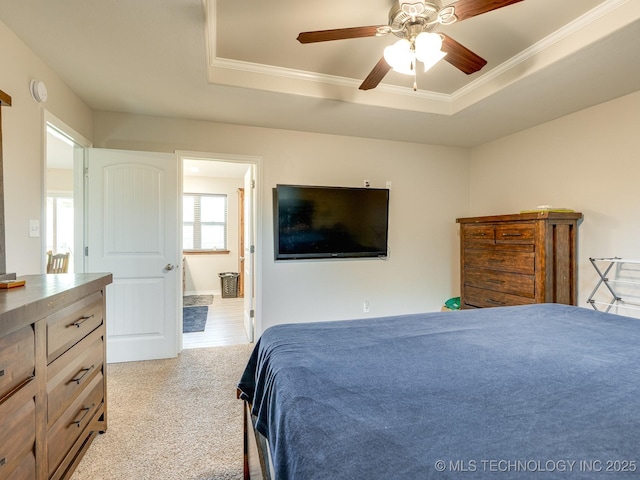 carpeted bedroom featuring ornamental molding, ceiling fan, and a raised ceiling