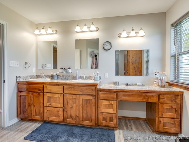 bathroom with a sink, baseboards, double vanity, and wood finished floors