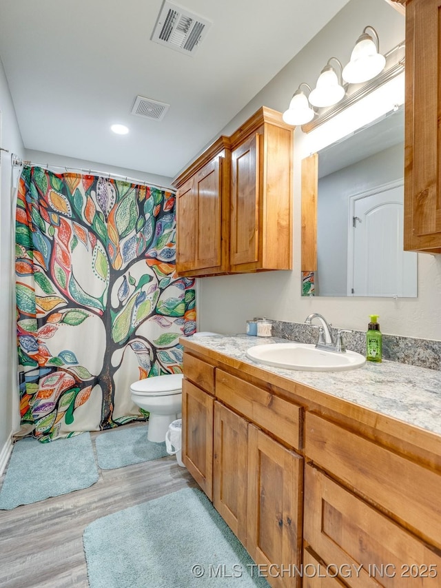 bathroom with visible vents, toilet, vanity, and wood finished floors