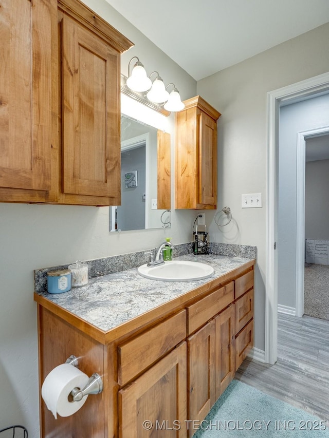 bathroom featuring vanity, baseboards, and wood finished floors