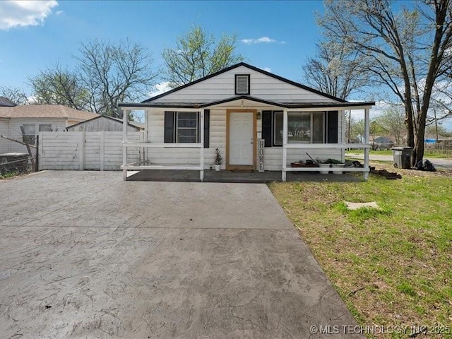 bungalow-style home featuring fence, a front lawn, and concrete driveway