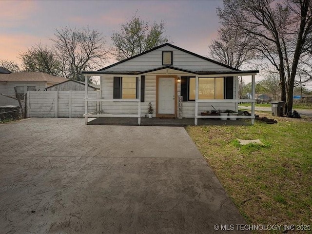 bungalow-style house with concrete driveway, fence, and a front yard