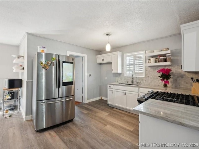 kitchen with white cabinets, wood finished floors, freestanding refrigerator, and a sink