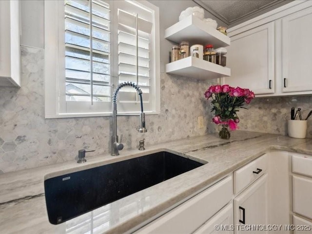 kitchen with open shelves, tasteful backsplash, white cabinetry, and a sink