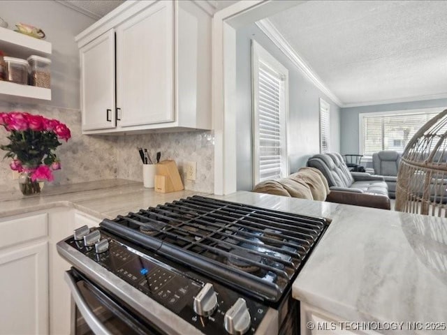 kitchen featuring stainless steel gas range oven, crown molding, tasteful backsplash, open floor plan, and white cabinetry