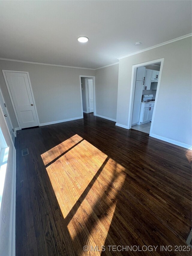 319 S Main St, Owasso, OK 74055 - unfurnished living room featuring visible vents, baseboards, crown molding, and dark wood finished floors