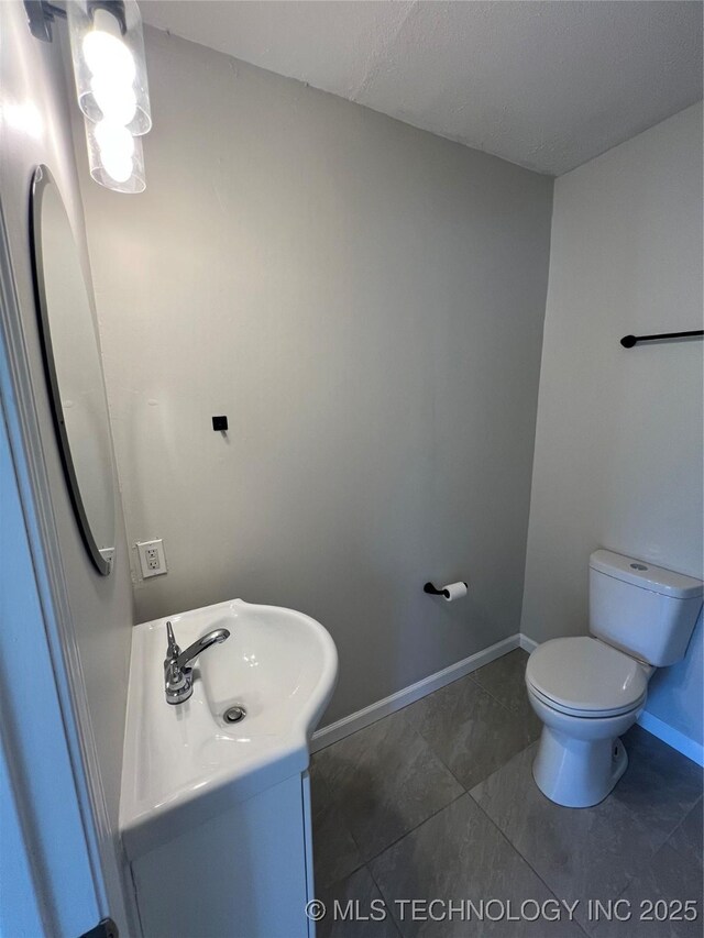 319 S Main St, Owasso, OK 74055 - bathroom with tile patterned floors, vanity, baseboards, and toilet