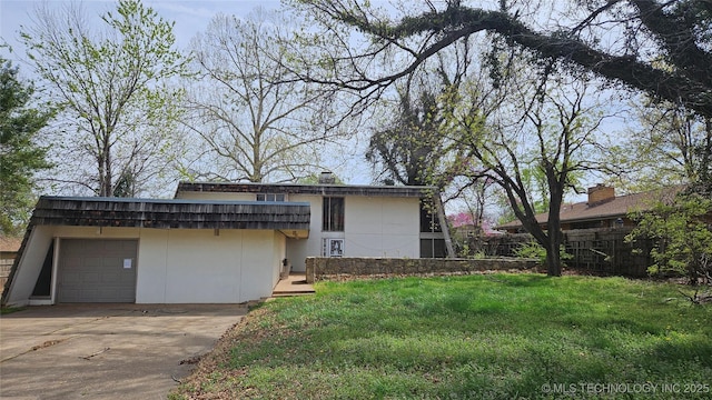 exterior space featuring concrete driveway, a yard, fence, and a garage