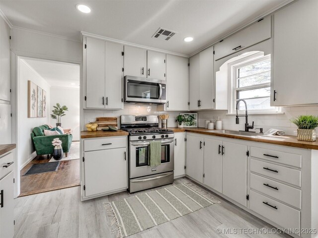 1809 N Delaware Pl, Tulsa, OK 74110 - kitchen with tasteful backsplash, light wood-type flooring, visible vents, appliances with stainless steel finishes, and a sink