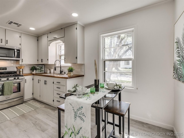 1809 N Delaware Pl, Tulsa, OK 74110 - kitchen featuring a sink, visible vents, light wood-type flooring, and appliances with stainless steel finishes