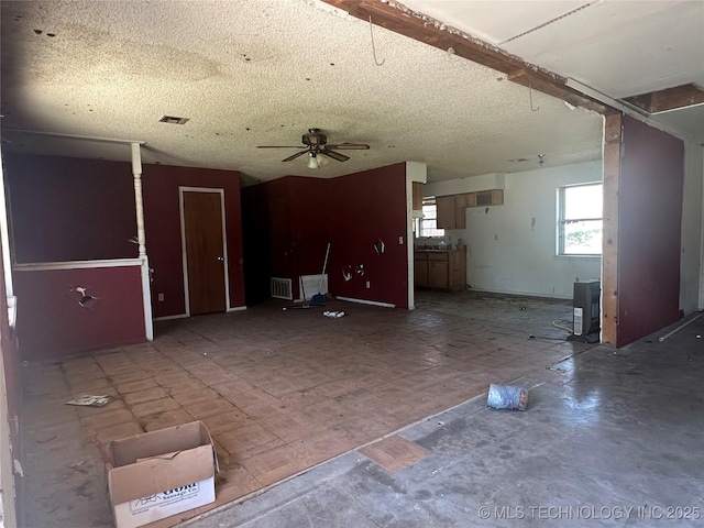 unfurnished living room featuring visible vents, a textured ceiling, and ceiling fan