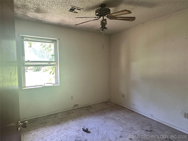 spare room with a textured ceiling, a ceiling fan, and visible vents