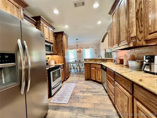 2516 Stage Coach Ave, Durant, OK 74701 - kitchen featuring visible vents, a peninsula, stainless steel appliances, backsplash, and light stone counters