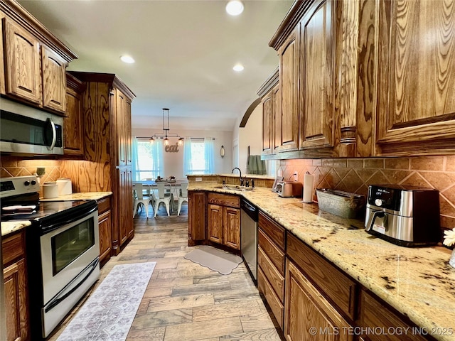 2516 Stage Coach Ave, Durant, OK 74701 - kitchen featuring light stone countertops, a peninsula, appliances with stainless steel finishes, a sink, and backsplash