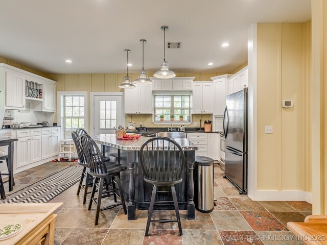 263 Eagles Nest Path, Stigler, OK 74462 - kitchen with white cabinets, a breakfast bar area, visible vents, and freestanding refrigerator