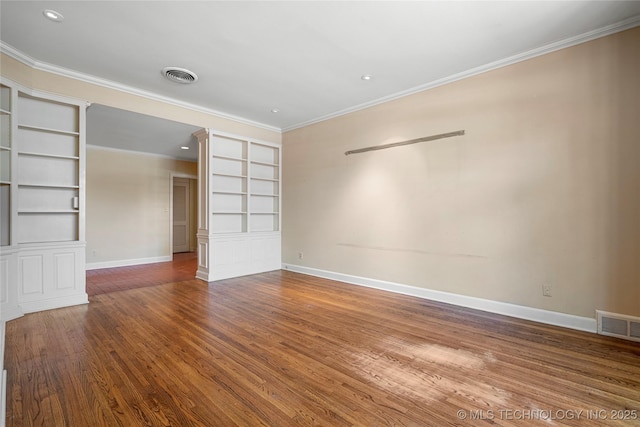spare room with crown molding, built in features, and visible vents
