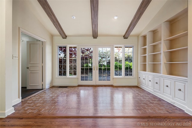 unfurnished living room with visible vents, beam ceiling, baseboards, and french doors