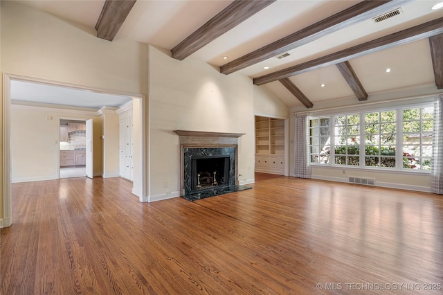 unfurnished living room featuring lofted ceiling with beams, wood finished floors, visible vents, and a fireplace