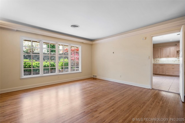 unfurnished room with a wealth of natural light, visible vents, and light wood-type flooring