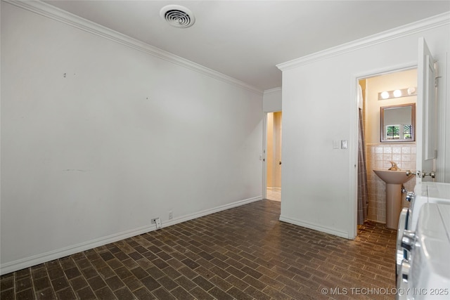 unfurnished room with brick patterned floor, visible vents, a sink, crown molding, and baseboards