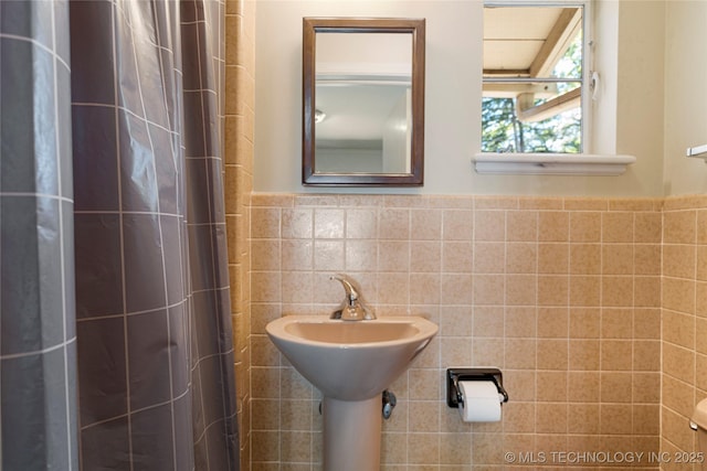 bathroom with curtained shower and tile walls