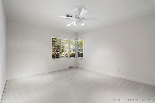 carpeted spare room featuring baseboards, a ceiling fan, visible vents, and ornamental molding