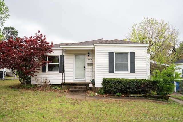 bungalow-style house featuring roof with shingles and a front lawn