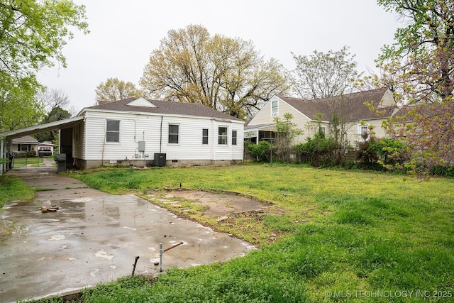 rear view of house featuring central AC unit, a yard, a carport, crawl space, and driveway