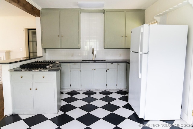 kitchen featuring a sink, tile patterned floors, freestanding refrigerator, and a peninsula