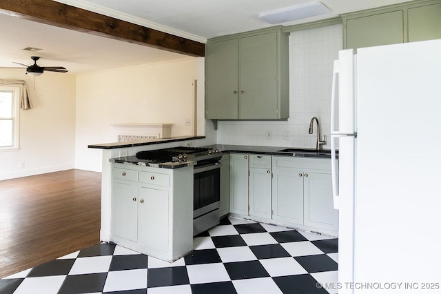 kitchen featuring a sink, freestanding refrigerator, dark countertops, a peninsula, and dark floors