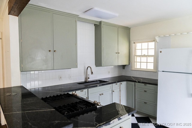 kitchen with tasteful backsplash, dark stone countertops, a sink, freestanding refrigerator, and range