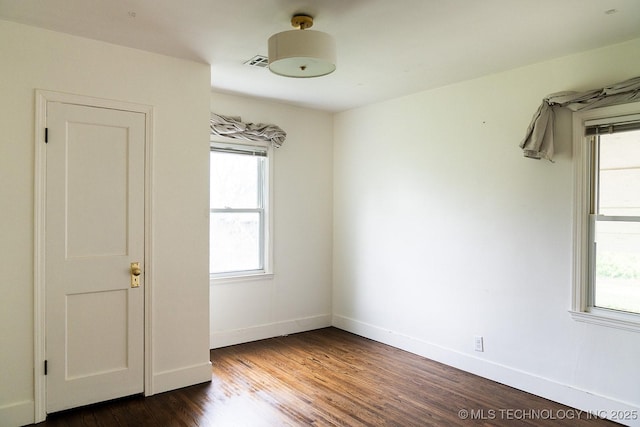 spare room with visible vents, dark wood-style flooring, baseboards, and plenty of natural light