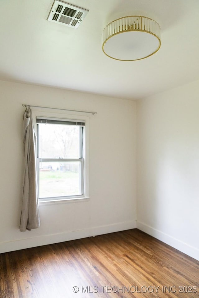 empty room featuring visible vents, baseboards, and wood finished floors
