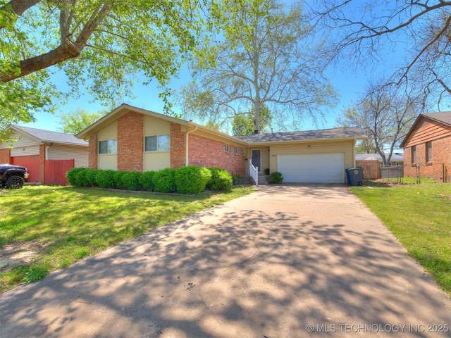 single story home with concrete driveway, an attached garage, a front lawn, brick siding, and fence