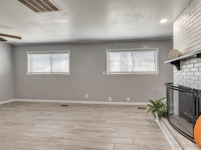 unfurnished living room featuring light wood finished floors, ceiling fan, a fireplace, and visible vents