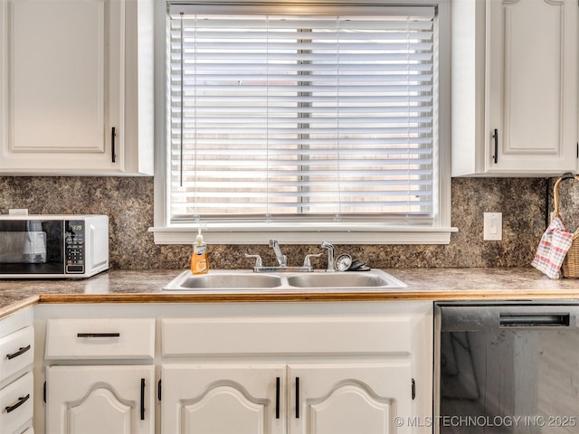 kitchen featuring a sink, a wealth of natural light, white cabinetry, and dishwashing machine