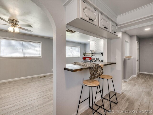 kitchen with visible vents, light wood-style flooring, ceiling fan, and baseboards