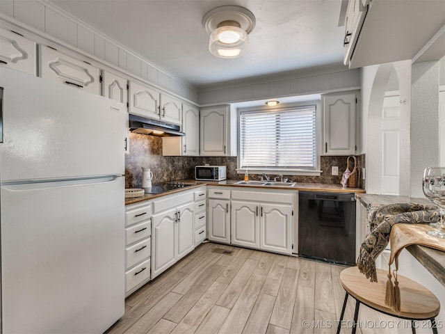 kitchen with backsplash, dark countertops, black appliances, under cabinet range hood, and a sink