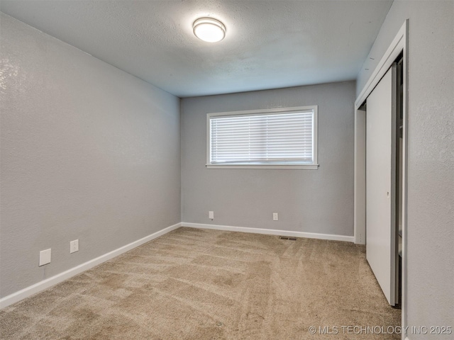 unfurnished bedroom featuring a closet, baseboards, visible vents, a textured ceiling, and carpet flooring