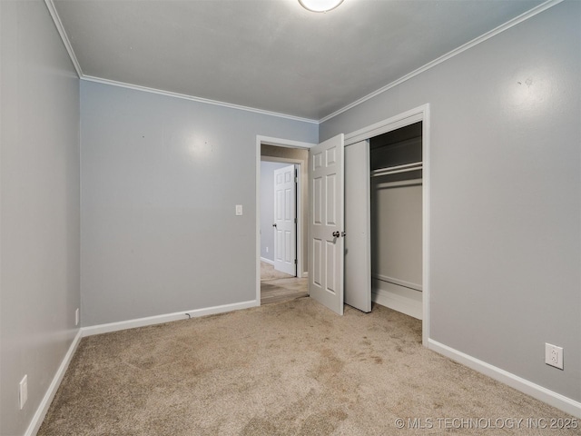 unfurnished bedroom with crown molding, a closet, baseboards, and carpet